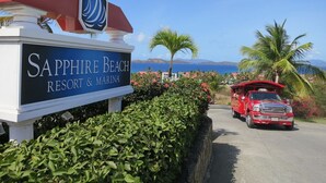 Une enseigne indiquant l’emplacement de Sapphire Beach Resort & Marina, avec un véhicule rouge garé devant.