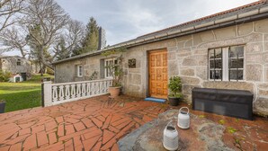 Un edificio de piedra con puerta de madera, plantas en macetas y un patio de ladrillo.