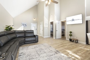 A spacious living room with a large L-shaped sectional sofa, a ceiling fan, and a mounted sign for RentBrinson.com. - Private Hot Tub, Free Tickets, Near Silver Dollar City & Community Indoor Pool (Kimberling City)