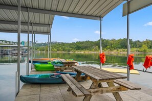A covered dock area with canoes, a picnic table, and life jackets. - On Table Rock Shoreline w/ Lake Views, Private Hot Tub, Billiards, Boat Slip & Cmty Amenities (Branson)