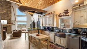 A spacious kitchen with wooden cabinets, a dining table, and a stone fireplace. - On Table Rock Shoreline w/ Lake Views, Private Hot Tub, Billiards, Boat Slip & Cmty Amenities (Branson)