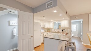 Une cuisine moderne avec des meubles blancs, un grand îlot central et un coin bar.