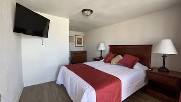 A hotel room with a bed, two bedside tables, a TV mounted on the wall, and a ceiling light.