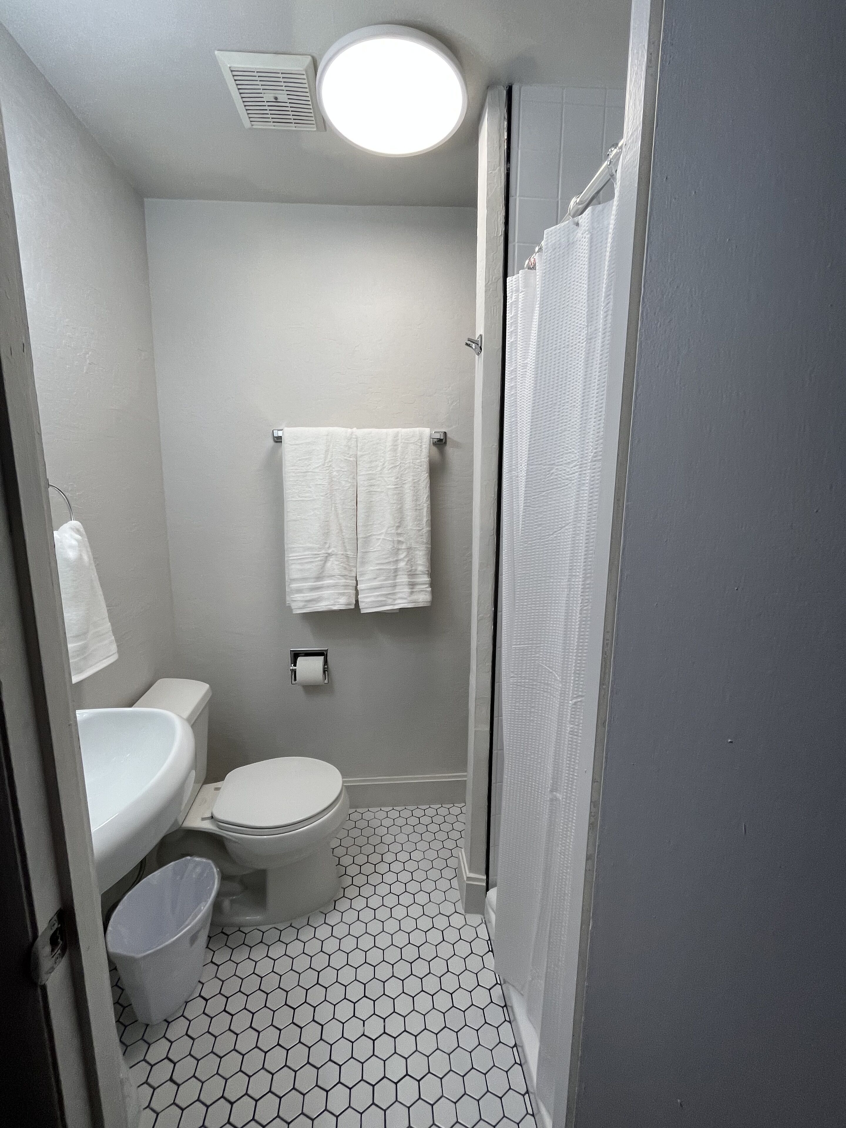 A compact bathroom with a toilet, sink, and shower.