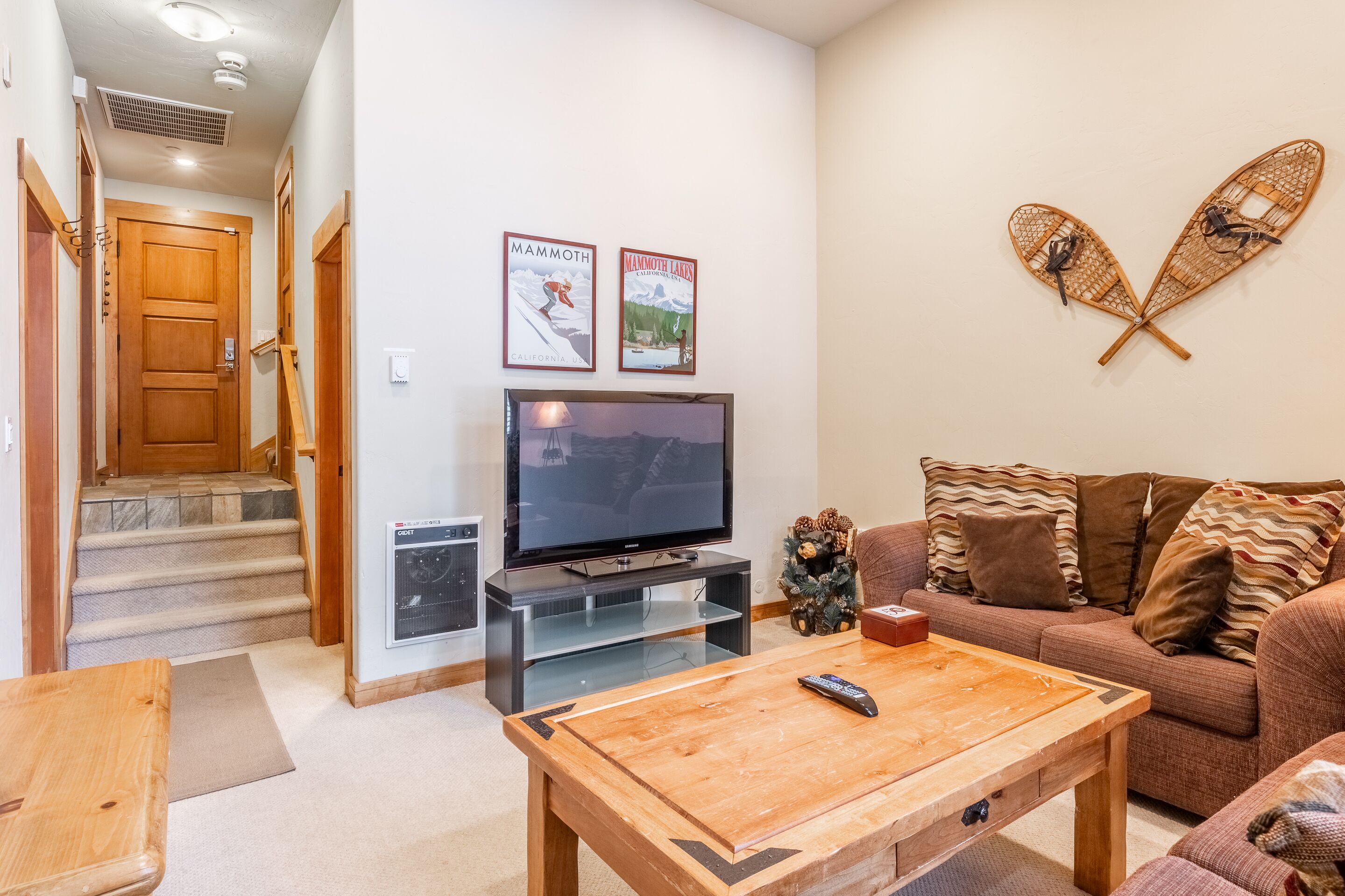 A living room with a TV, wooden coffee table, and a couch with patterned cushions.