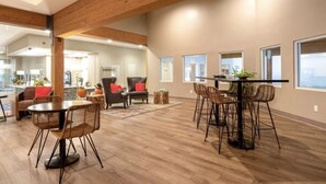 A spacious living area with a high ceiling, wooden beams, and a dining table with chairs.
