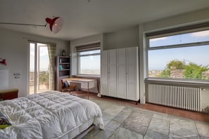 Een slaapkamer met een bed, een bureau en uitzicht op de stad.