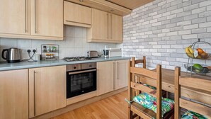 Una cocina moderna con armarios de madera, estufa a gas, horno y comedor con mesa y sillas de madera.