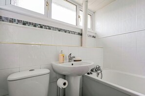 Een badkamer met toilet, wastafel en bad.