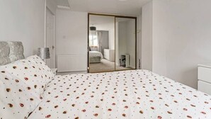 Un dormitorio con cama, armario, radiador y puerta que da a otra habitación.