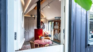 A cozy dining area with a red and white checkered tablecloth, a red cabinet, and a window with a view of the outside. - The Little House, Orford (Orford)