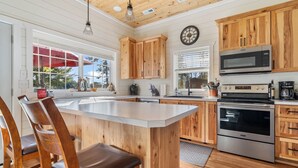 Una cocina con armarios de madera, una isla grande, electrodomésticos de acero inoxidable y un paraguas rojo en el exterior.
