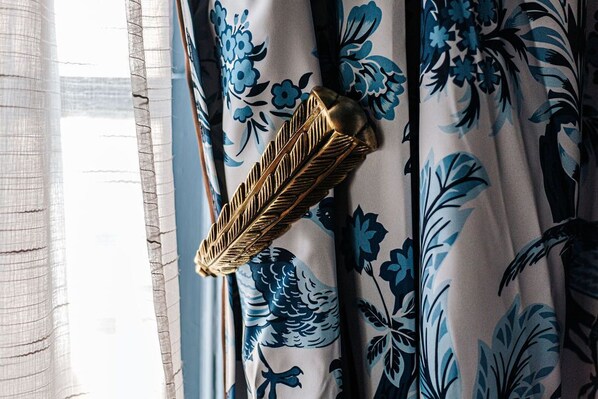 Una ventana con cortinas translúcidas y un objeto dorado decorativo en el marco.