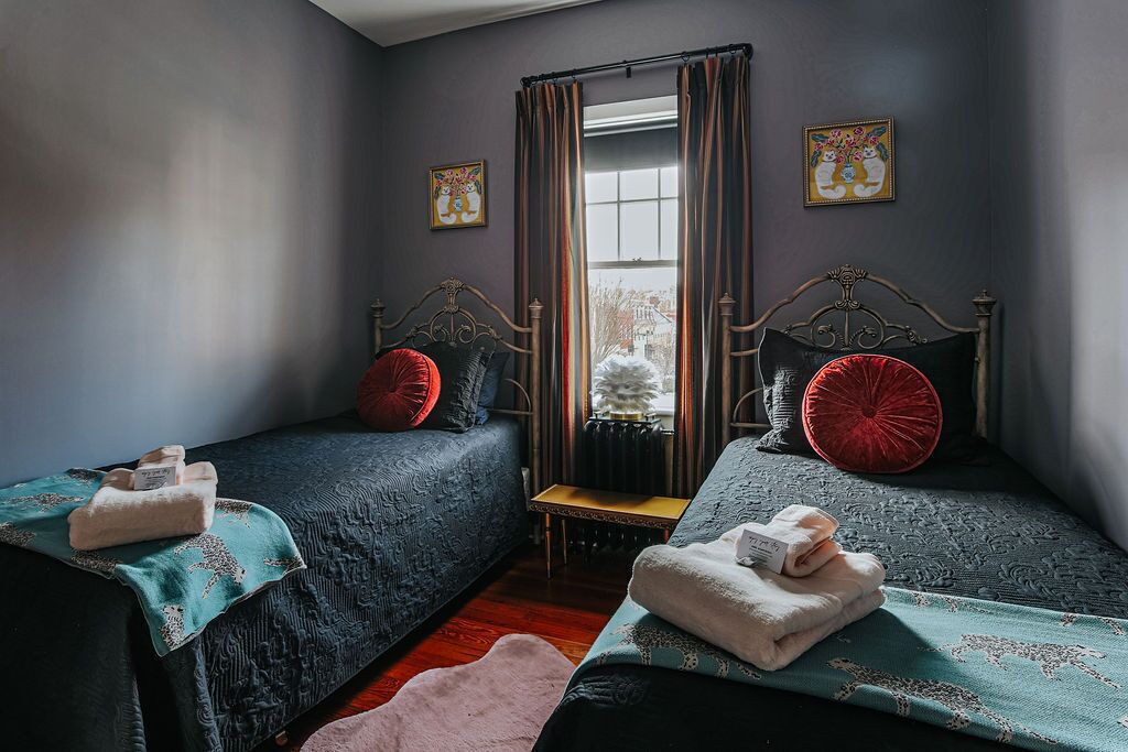 Une chambre avec deux lits, une fenêtre avec des rideaux et un radiateur.