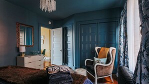 A bedroom with a bed, a chair, a dresser, and a door.