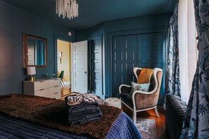Een slaapkamer met een bed, een stoel, een kast en een deur.