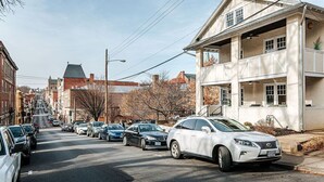 A street with parked cars and a building with a balcony.