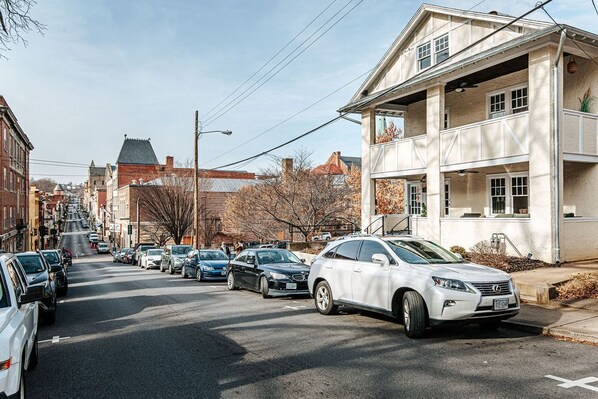 Una calle con coches estacionados y un edificio con balcón.