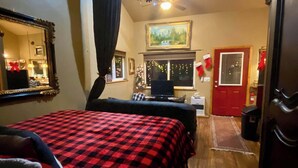 A cozy room with a bed, a desk, a computer, and a window with a view of a forest. - Bear Cabin-Gunning Cabin Rentals (Soldotna)