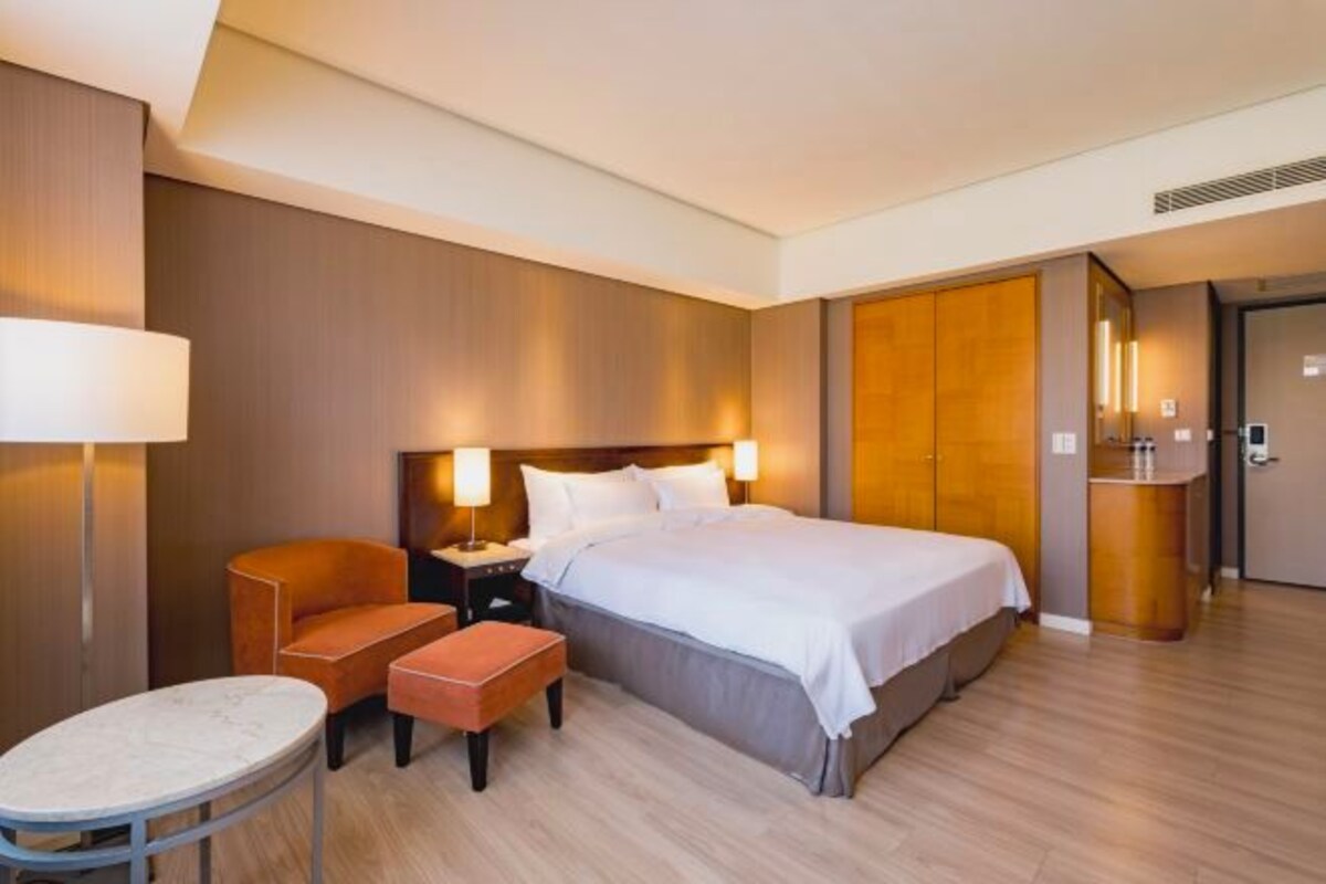 A hotel room with a bed, a desk, a chair, and a small table.