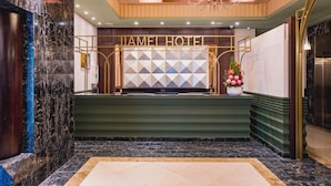 A reception area with a marble reception desk, a chandelier, and a geometric wall design. -  Jiamei Hotel (Taipei)