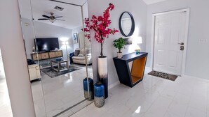 Una sala de estar moderna con un espejo grande, un sofá, una mesa de centro y una televisión.