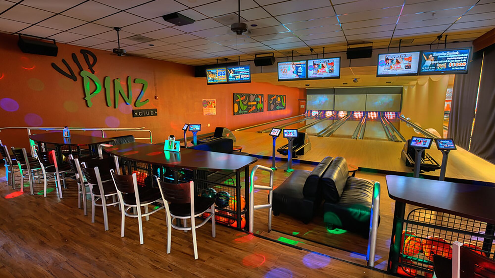 En bowlinghall med flera banor, sittplatser och en vägg med en skylt som visar att det finns en "VIP PINZ-klubb".