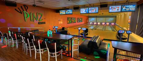 En bowlinghall med flera banor, sittplatser och en vägg med en skylt som visar att det finns en "VIP PINZ-klubb".