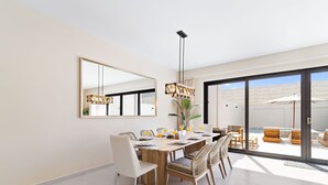 A dining area with a wooden table, white chairs, and a large mirror on the wall. - 4BR Private Pool & Jacuzzi Boca Catalina Beach (Noord)