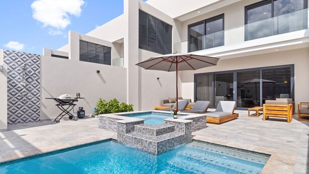 A modern outdoor pool area with a hot tub, lounge chairs, and a grill. - 4BR Private Pool & Jacuzzi Boca Catalina Beach (Noord)