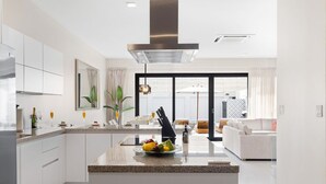 A modern kitchen with white cabinets, a granite countertop, and a central island with fruit. - 4BR Private Pool & Jacuzzi Boca Catalina Beach (Noord)