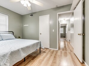 A bedroom with a bed, a ceiling fan, a door, and a hallway. -  COZY 3 BEDROOM  HOUSE NEAR WILL ROGERS INTERNATIONAL AIRPORT AND DOWNTOWN OKC (Oklahoma City)
