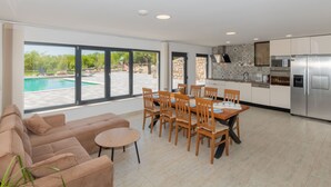Eine moderne Küche mit Essbereich, großen Fenstern und Blick auf einen Pool.