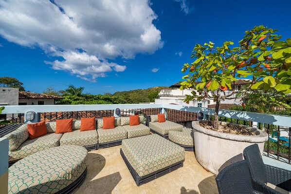 A rooftop patio with a sectional sofa, outdoor chairs, and a potted plant. - 2-Min to Beach | Private Pool & 360° Rooftop Views - Casa Cazenovia 3 Bedroom Home (Las Catalinas)