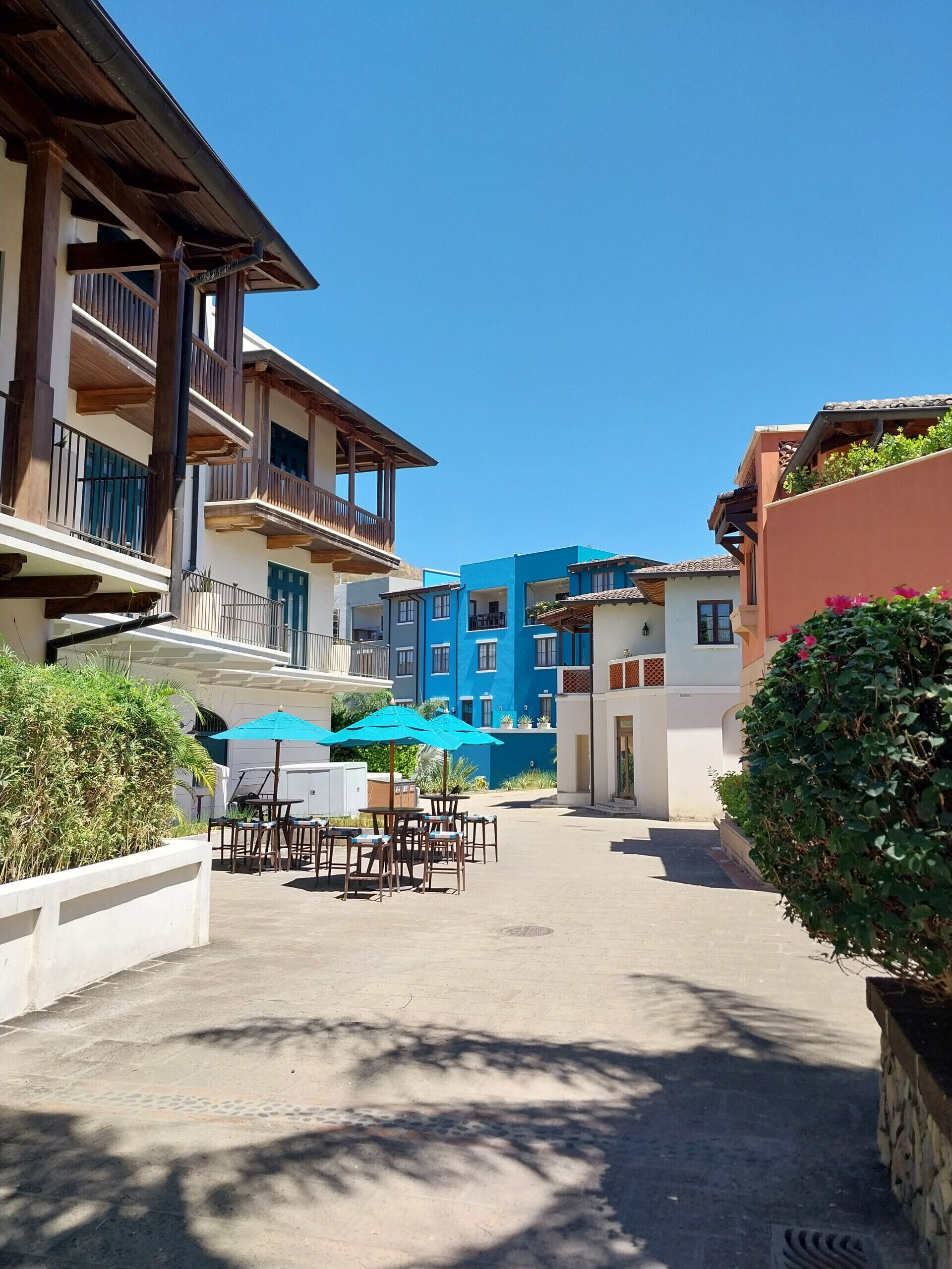 A courtyard with outdoor seating, a pool, and buildings with balconies and windows.