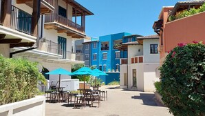 Un patio con mobiliario exterior, piscina y edificios con balcones y ventanas.