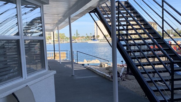 Un espacio al aire libre techado con vista al agua, una escalera y una silla.