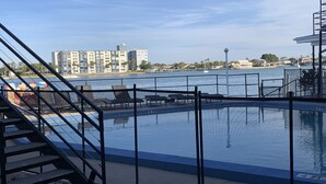 Una piscina con vistas a un puerto deportivo y edificios al fondo.