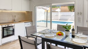 Eine moderne Küche mit Essbereich und Blick auf einen Pool.