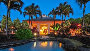 A hotel with a pool, palm trees, and a well-lit entrance. - OCEANFRONT RESORT, cascading ponds, daily fresh towel exchanges, hiking path (Koloa)