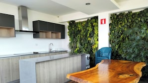 A modern kitchen with a central island, dark cabinets, and a green leafy wall. - Suite Zen (Guatemala City)