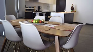 A modern kitchen with a dining table, chairs, and a fruit bowl. - Suite Zen (Guatemala City)
