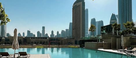 A rooftop pool area with lounge chairs and a view of the Dubai skyline.
