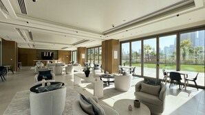 A spacious, modern living area with multiple seating arrangements, large windows offering city views, and a visible kitchen area. - Dubai Mall Access Burj Khalifa Infinity Pool | 4BR (Dubai)