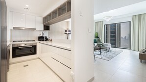 A modern kitchen with white cabinetry, a built-in oven, and a gas stove. - Dubai Mall Access Burj Khalifa Infinity Pool | 4BR (Dubai)