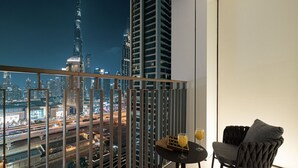 A balcony with a view of a city skyline, including a prominent tower, and a table with two glasses of orange juice. - Dubai Mall Access Burj Khalifa Infinity Pool | 4BR (Dubai)
