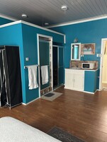 Un baño con ducha, lavamanos, espejo y microondas.