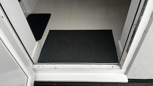 Une porte avec un paillasson noir et un tapis d’entrée.