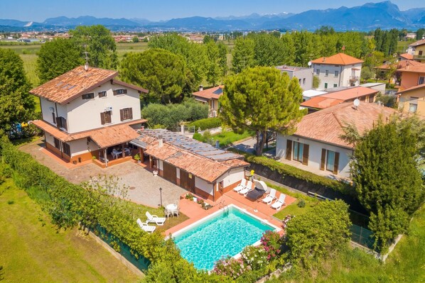 Una casa grande con piscina, varias habitaciones y un jardín.