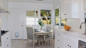 A kitchen with white cabinets, a round dining table with chairs, a sink, and a window with a view of the outdoors. - Spacious 2br 2ba in the heart of Belvedere, minutes walking to downtown Tiburon (Belvedere)